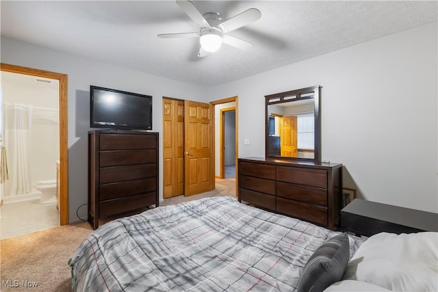 bedroom with ceiling fan, ensuite bath, and light colored carpet