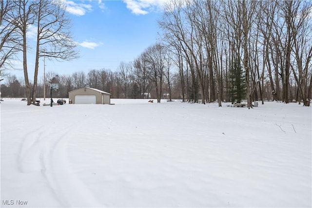 snowy yard featuring a garage and an outdoor structure