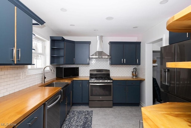 kitchen featuring blue cabinetry, wall chimney range hood, and black appliances