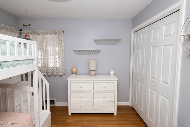 bedroom featuring a crib, a closet, and wood-type flooring