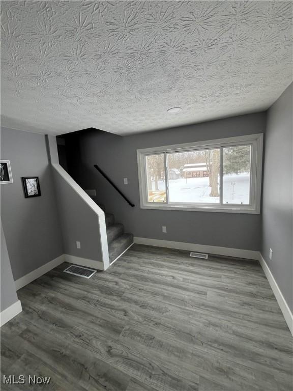 unfurnished living room featuring hardwood / wood-style flooring, a healthy amount of sunlight, and a textured ceiling