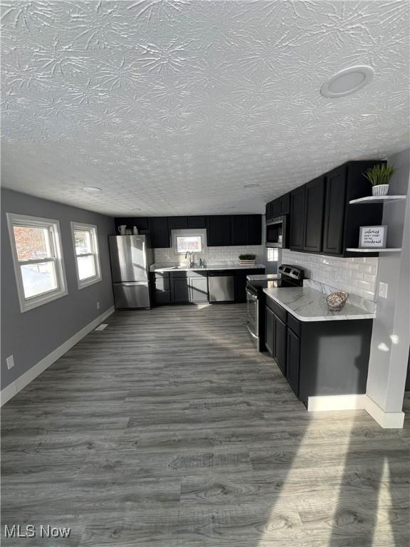 kitchen with backsplash, dark wood-type flooring, and appliances with stainless steel finishes