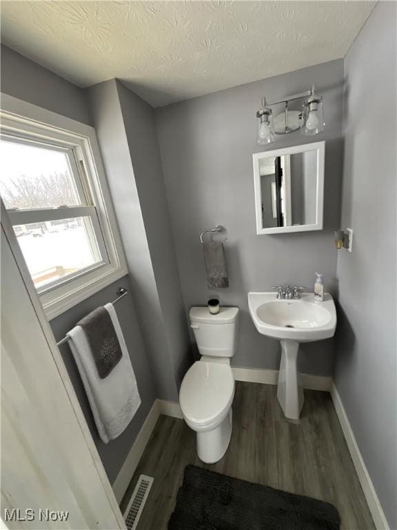 bathroom with hardwood / wood-style flooring, a textured ceiling, and toilet