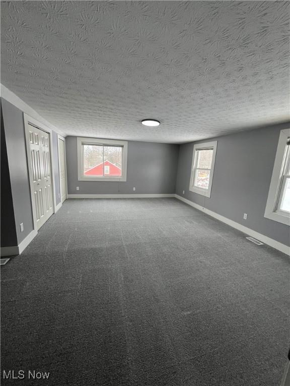 carpeted empty room with a textured ceiling