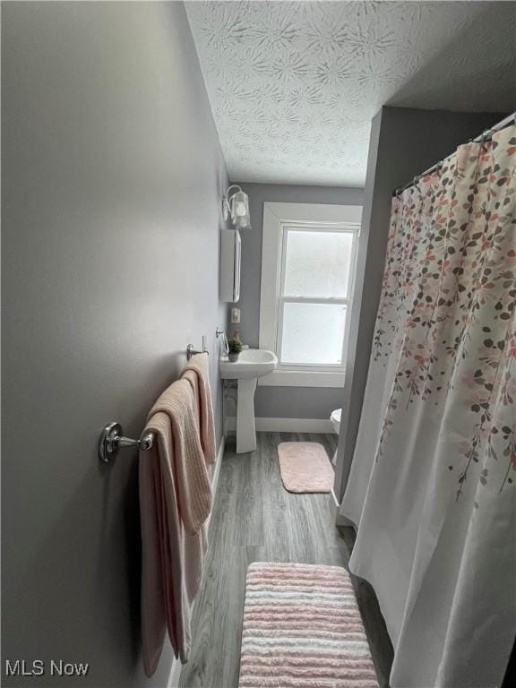 bathroom with toilet, hardwood / wood-style floors, and a textured ceiling