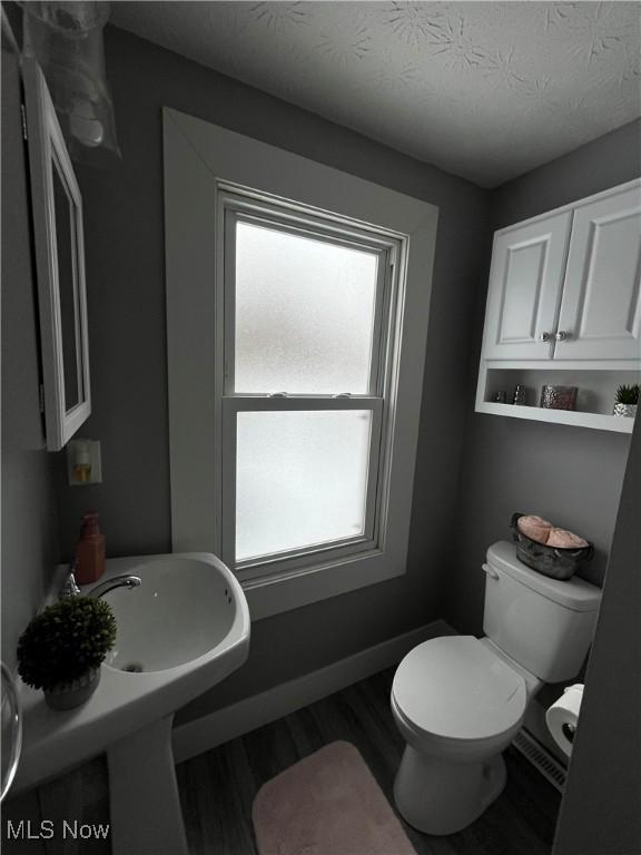 bathroom with wood-type flooring, a textured ceiling, and toilet