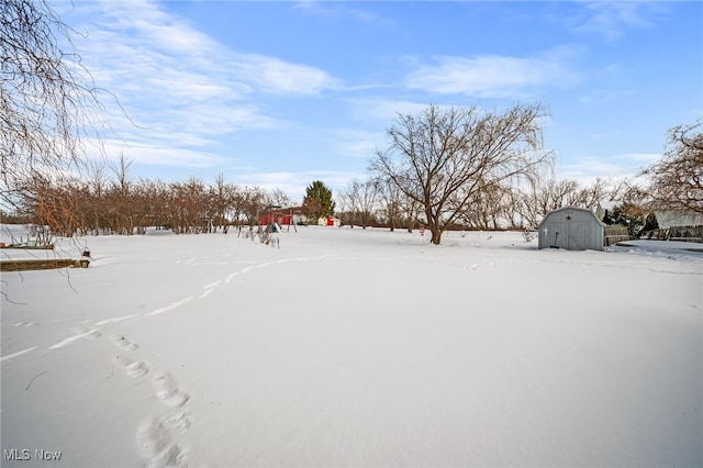 yard covered in snow with a storage shed