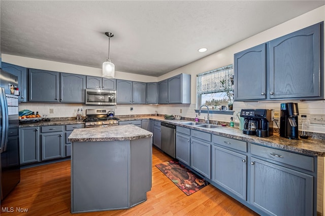 kitchen with appliances with stainless steel finishes, a center island, sink, and blue cabinetry