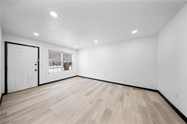 empty room featuring light hardwood / wood-style floors and a textured ceiling