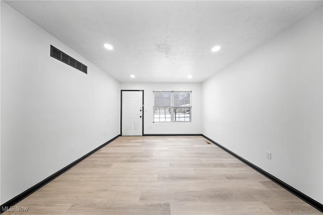 spare room featuring light hardwood / wood-style floors and a textured ceiling