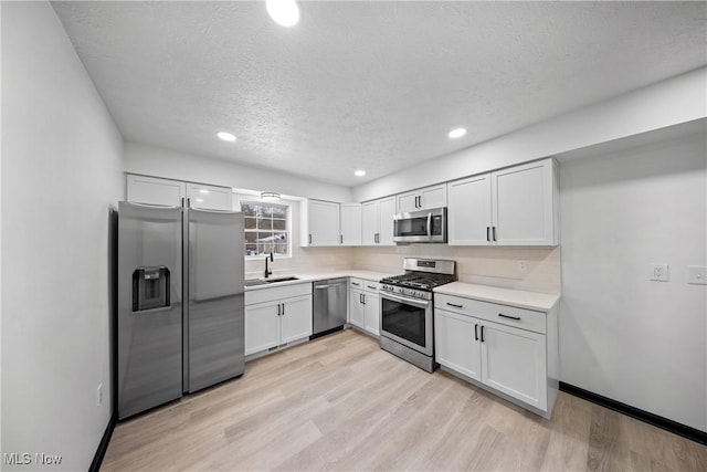 kitchen featuring sink, light hardwood / wood-style floors, white cabinets, and appliances with stainless steel finishes