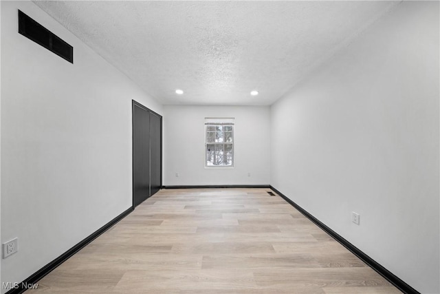 spare room featuring light hardwood / wood-style flooring and a textured ceiling