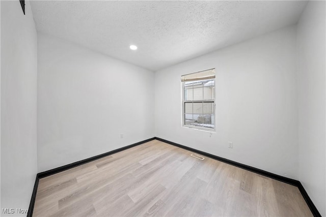 empty room featuring light hardwood / wood-style floors and a textured ceiling