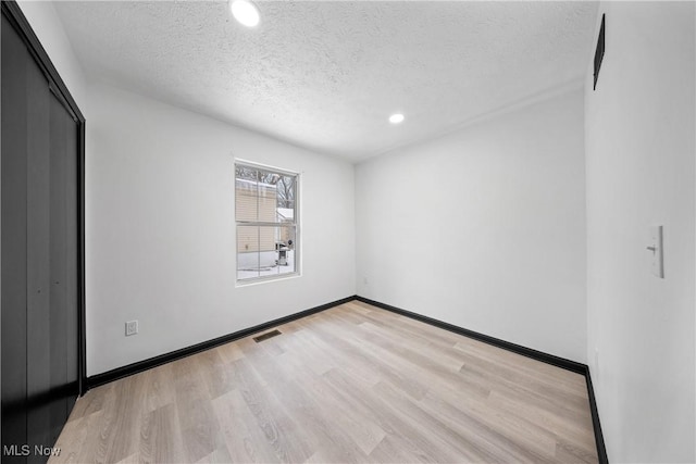 spare room featuring light hardwood / wood-style floors and a textured ceiling