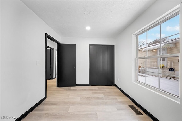 unfurnished bedroom with light hardwood / wood-style flooring and a textured ceiling