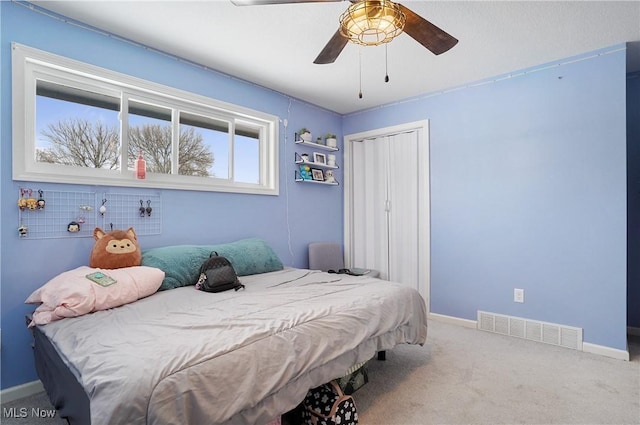 carpeted bedroom featuring ceiling fan and a closet