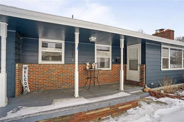 snow covered property entrance with a porch