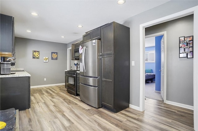 kitchen featuring stainless steel appliances, light stone countertops, and light hardwood / wood-style flooring