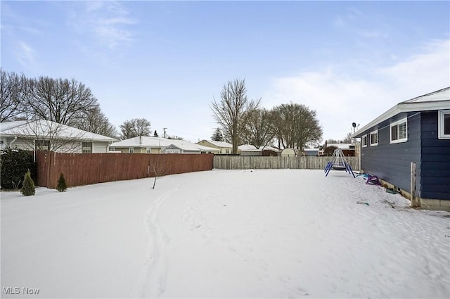 snowy yard featuring a playground