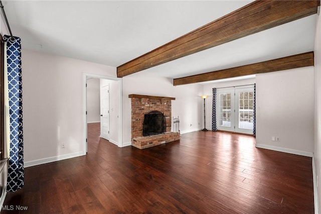 unfurnished living room featuring a brick fireplace, dark hardwood / wood-style floors, beamed ceiling, and french doors