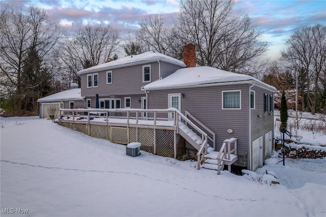 snow covered back of property featuring a wooden deck