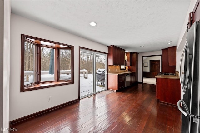 kitchen with sink, dark hardwood / wood-style flooring, decorative backsplash, stainless steel appliances, and a textured ceiling