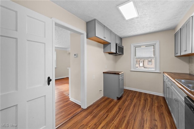 kitchen featuring dark hardwood / wood-style flooring, gray cabinets, a textured ceiling, and appliances with stainless steel finishes