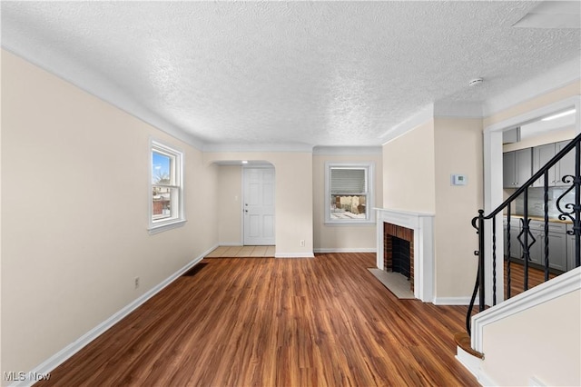 unfurnished living room featuring a fireplace, dark hardwood / wood-style flooring, and a textured ceiling