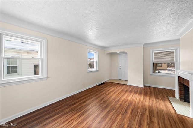 unfurnished living room featuring a fireplace, dark hardwood / wood-style flooring, and a textured ceiling