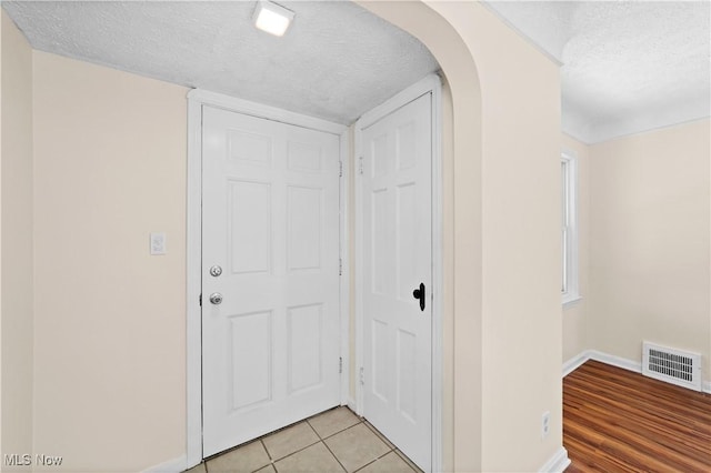 hallway featuring light tile patterned floors and a textured ceiling