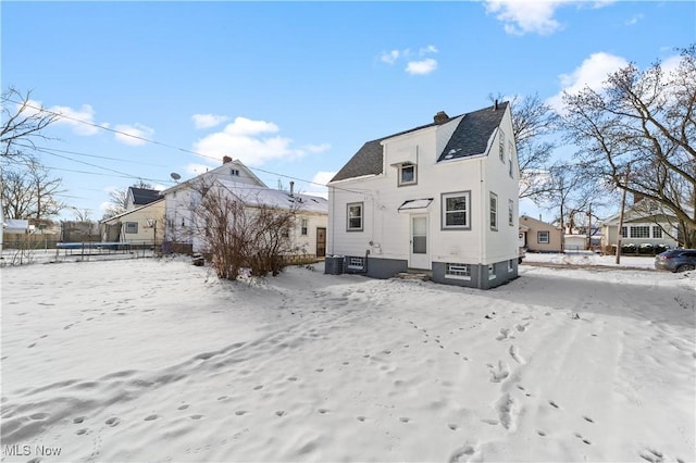 snow covered back of property featuring a trampoline and central air condition unit