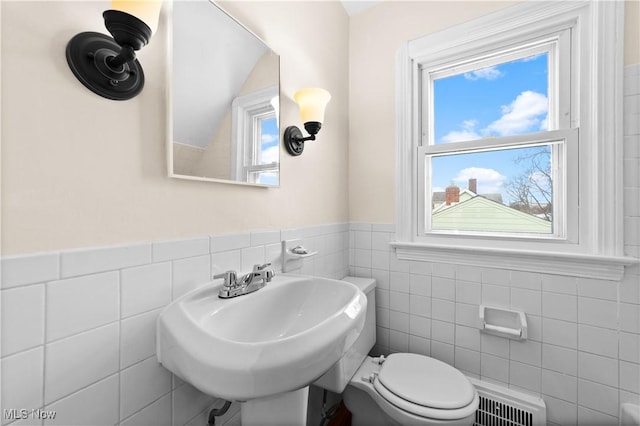 bathroom featuring toilet, sink, and tile walls