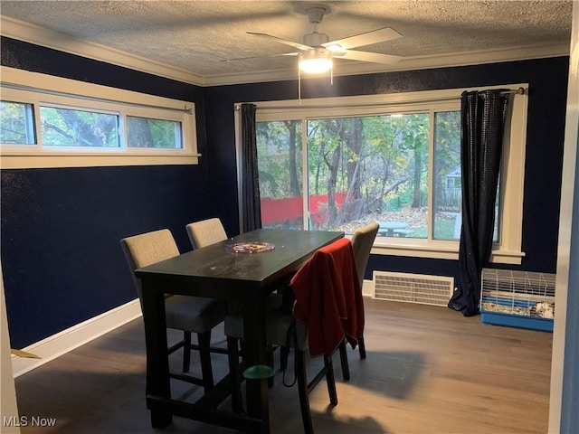 dining space featuring hardwood / wood-style flooring, ornamental molding, a textured ceiling, and ceiling fan