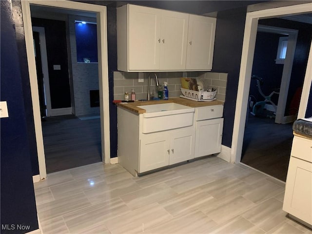 kitchen with white cabinetry, butcher block counters, sink, and decorative backsplash