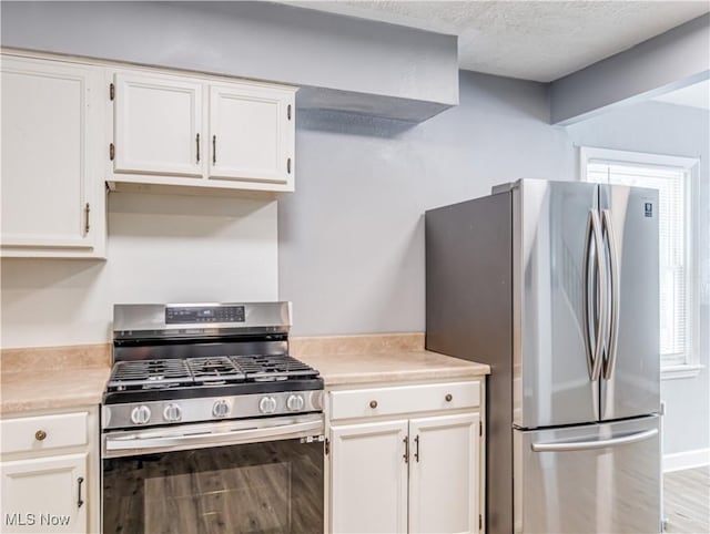 kitchen with appliances with stainless steel finishes, light wood-type flooring, and white cabinets