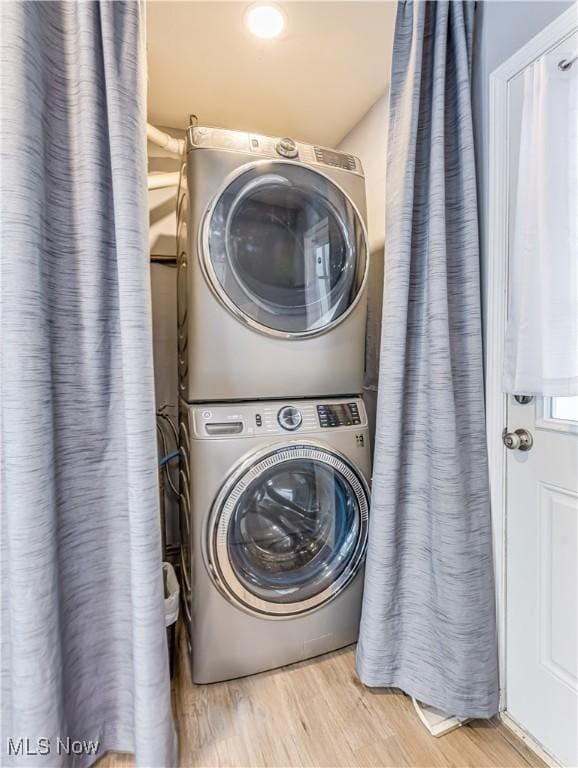 clothes washing area featuring stacked washer / dryer and light hardwood / wood-style floors