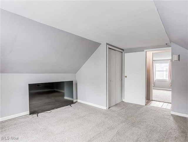 bonus room with light colored carpet and lofted ceiling