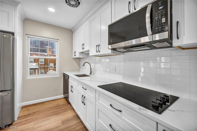 kitchen featuring stainless steel appliances, white cabinetry, and light stone countertops