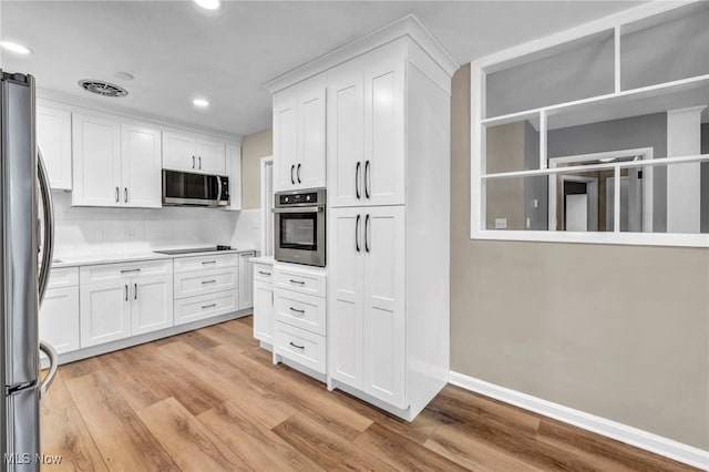 kitchen with stainless steel appliances, light wood-type flooring, decorative backsplash, and white cabinets