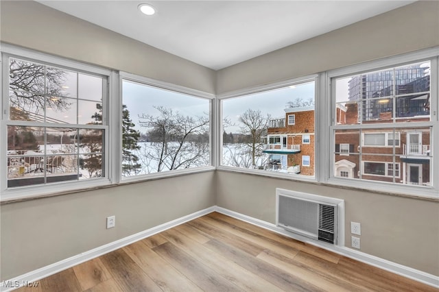 unfurnished sunroom featuring a wall mounted air conditioner and a wealth of natural light