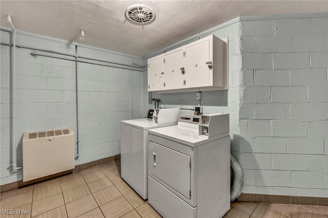 laundry room with a textured ceiling, cabinets, and washing machine and clothes dryer