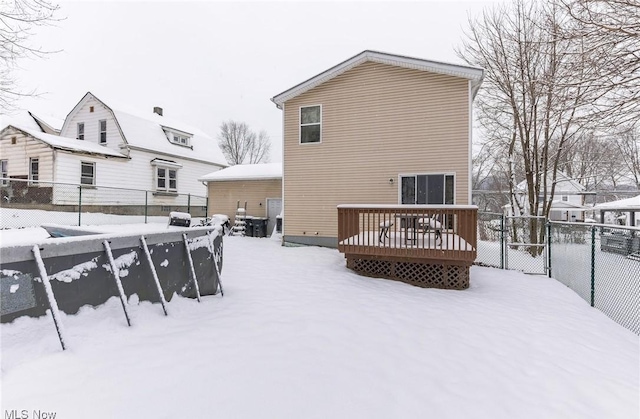 snow covered back of property featuring a wooden deck