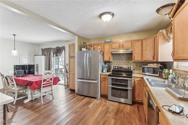 kitchen featuring stainless steel appliances, sink, hanging light fixtures, and plenty of natural light