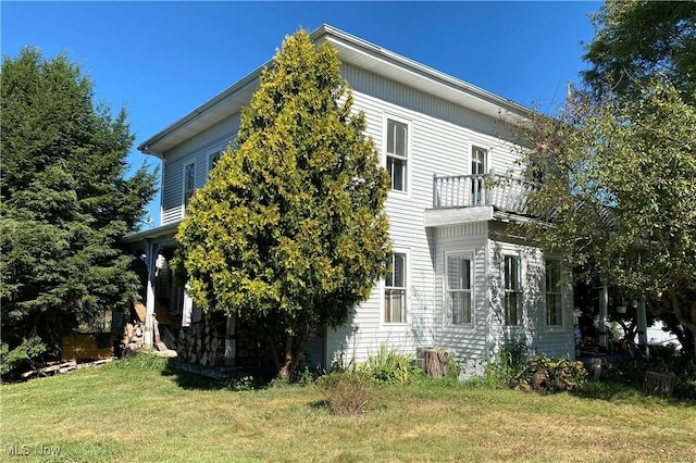 view of side of property featuring a lawn and a balcony