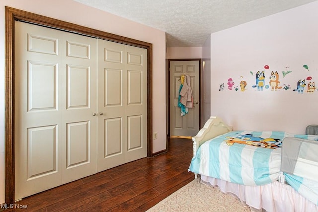 bedroom with dark wood-type flooring, a textured ceiling, and a closet