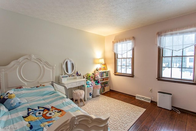 bedroom with dark hardwood / wood-style floors and a textured ceiling