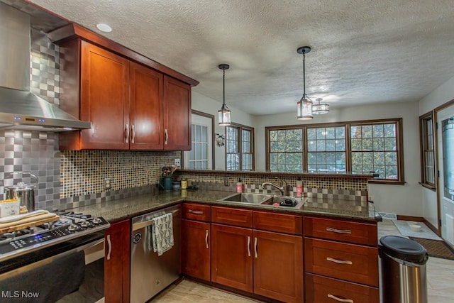 kitchen featuring sink, hanging light fixtures, wall chimney range hood, stainless steel appliances, and backsplash