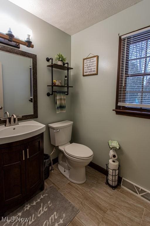 bathroom with vanity, wood-type flooring, a textured ceiling, and toilet