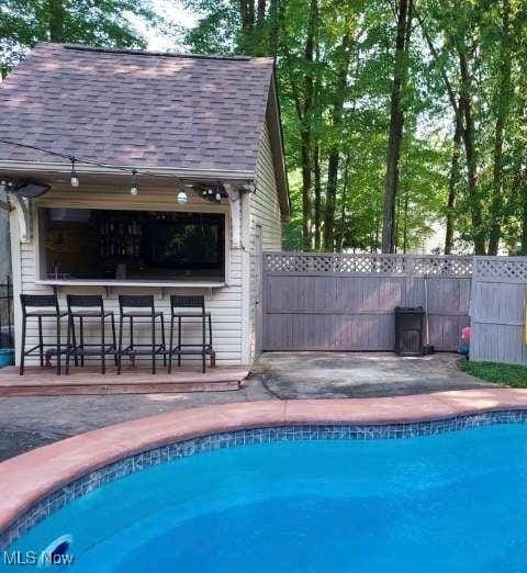 view of pool with an outdoor bar and a patio