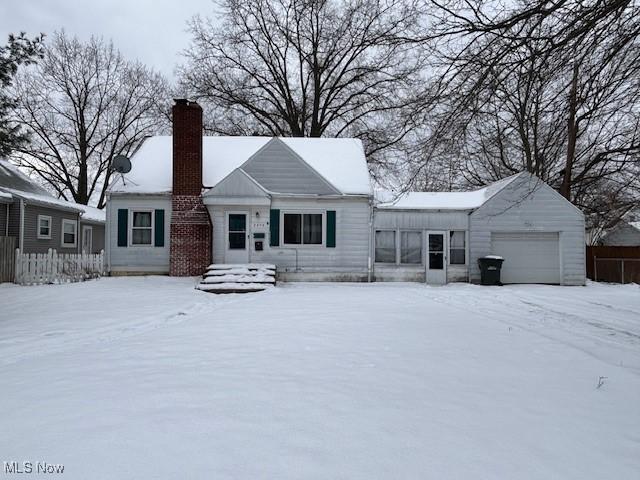 snow covered rear of property with a garage